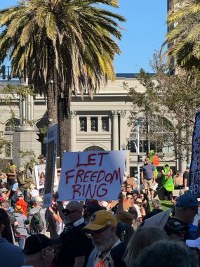 Bir grup protestocu arasında gamalı haç betimlemeli otoriter bir figürün karikatürünü gösteren kışkırtıcı bir poster yer alıyor. İşaret demokrasiye yönelik tehditleri ve Krallar Yok temasını ele alıyor..