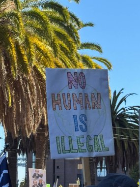 NoHUMANISILLEGAL yazan el boyalı bir tabela, NoKings 'in mesajları arasındaki göç haklarını vurgulayan mitingdeki kalabalıkta bekletildi.