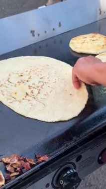 Bir satıcı, büyük boy pupaları dumanı tüten sıcak bir ızgaranın üzerine dikkatlice yerleştirir. Otantik sokak yiyecekleri için duman çıkarır ve yakar..