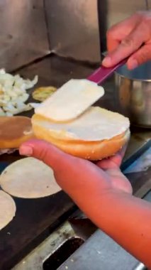 Bir aşçı, hamburgerin üzerine bir dilim beyaz peynir koyar. Sandviç ya da hamburgerciye hazırlanır..