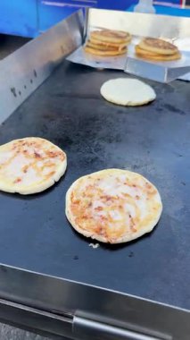 Pupusa çevirme, spatula ile yemek pişirme, ızgara pupa, Salvador yemeği, düz tava, altın köfte, etnik mutfak, açık hava tedarikçisi, istiflenmiş pupusas, Latin Amerika atıştırmalığı, hareketli yemek