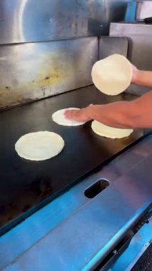 Meksika sokak yemeği standında taco montajında kullanılmadan önce sıcak ızgarada taze mısır tortillası ısıtılıyor..