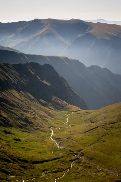 Vale verde com um rio e montanhas no nevoeiro da manhã no fundo, montanhas dos Cárpatos, Romênia — Fotografia de Stock