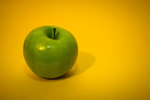 Πράσινο μήλο για το κίτρινο φόντο — Φωτογραφία Αρχείου