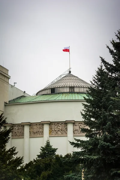 Budynek Parlamentu polskiego z drzewami i polską flagą — Zdjęcie stockowe