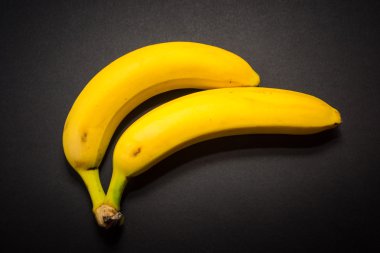 Siyah arka plan üzerine iki sarı muz