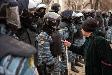 KYIV, UKRAINE DEC 1, 2011 Yaşlı kadın Ukraynalı Verkhovna Rada (Parlamento) yakınlarında Çernobil kurbanlarının gösterisi sırasında Berkut çevik kuvvet polisini sopayla tehdit etti