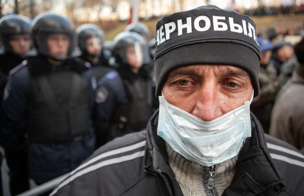 KYIV, UKRAINE DEC 1, 2011 Tıbbi maskeli adam Ukraynalı Verkhovna Rada (Parlamento) yakınlarında Çernobil kurbanlarının gösterisi sırasında kafasında 