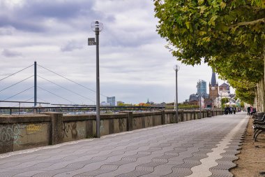 Ren Nehri boyunca Boş Ağaçlı Gezinti Alanı. Bulutlu Sonbahar Dsseldorf Almanya 'sında Uzak Kilise Spire ve Şehir Skyline' ı var.