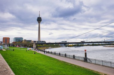 İkonik Rheinturm Kulesi ve Bulutlu Sonbahar Gökyüzü Altında Şehir Köprüsü ile Dsseldorf Almanya 'da Manzaralı Ren Nehri Gezintisi