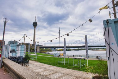 Rheinturm Kulesi ve Dsseldorf Almanya 'sında Rhine Nehri' ne bakan String Lights ve Şemsiyeli Riverside Cafe 'nin dışında.