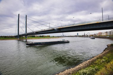 Cloudy Autumn Dsseldorf Almanya 'sında uzak şehir Skyline ile Rhine Nehri üzerinde Kablo Kalmış Köprü altında Kargo Mavnaları