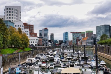 Gehry, Almanya 'nın Dsseldorf şehrinde Limanda Tekneler ve Sonbahar Ağaçlarıyla Yoğun Limana Bakan Çarpık Binalar Tasarladı