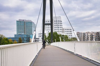 Dsseldorf Almanya 'sında Gehry Twisted Buildings ve City Skyline' la Beyaz Yaya Köprüsünde Binen Bisikletçi