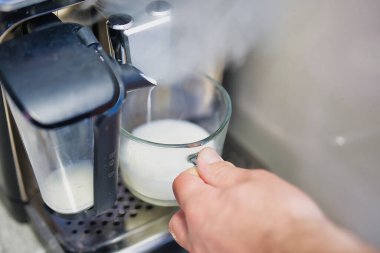 Bright Kitchen 'daki kahve makinesinden elde tutulan köpüklü köpüklü süt köpüklü süt.