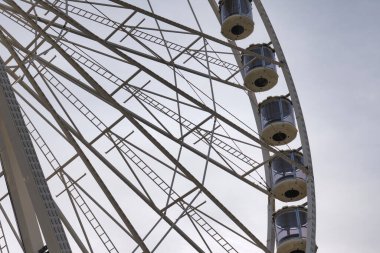 Dönme dolabın yakın çekim görüntüsü çerçevesini ve kabinlerini bulutlu bir gökyüzüne karşı gösteriyor..