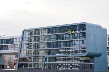 A sleek, modern office building of a technology company stands in a bustling cityscape during daylight.