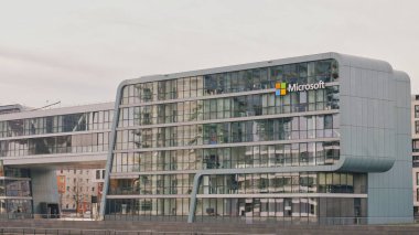 A sleek, glass office building stands in a busy city, showcasing modern architecture and design elements.