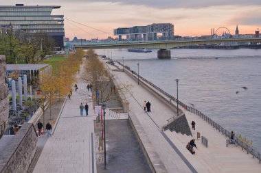 Gezginler, güneş batarken nehir kenarındaki geçidin keyfini çıkarırlar. Şehrin üzerine sıcak bir parıltı yayarlar..