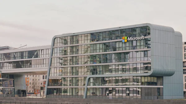 A sleek, glass office building stands in a busy city, showcasing modern architecture and design elements.