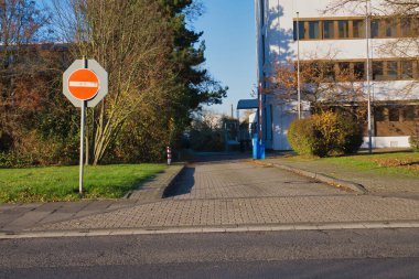 Almanya 'nın Neuss kentindeki bir caddenin manzarasında patika boyunca girişi yasaklanmış bir tabela bulunuyor. Sahnede, sonbaharda tipik bir kent manzarasının yer aldığı yakınlardaki binalar ve yeşillikler yer alıyor..
