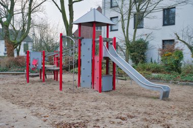 Terk Edilmiş Gri ve Kırmızı Oyun Alanı Yapısı Sandy Alanındaki Kaygan Duvar ve Çatı Ağaçlar ve Banliyö Apartmanı 'ndaki Modern Apartman Binaları