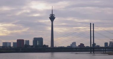 Bulutlu bir günde Rheinturm Kulesi ve Oberkassel Köprüsü ile Düsseldorf Nehri Skyline