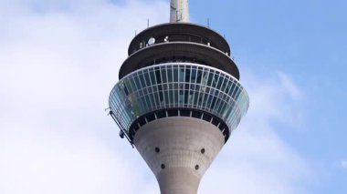 Rheinturm Dsseldorf TV Kulesi Almanya 'da mavi gökyüzüne karşı gözlem güvertesini ve modern cam mimariyi kapatır
