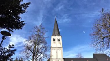 Yavaşça yukarı doğru hareket eden kamera Almanya 'da dramatik mavi gökyüzüne karşı kilise kulesini gösteriyor.