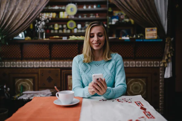 Porträt einer niedlichen blonden Frau liest etwas auf ihrem Smartphone — Stockfoto