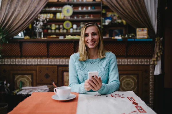 Porträt einer niedlichen blonden Frau liest etwas auf ihrem Smartphone — Stockfoto