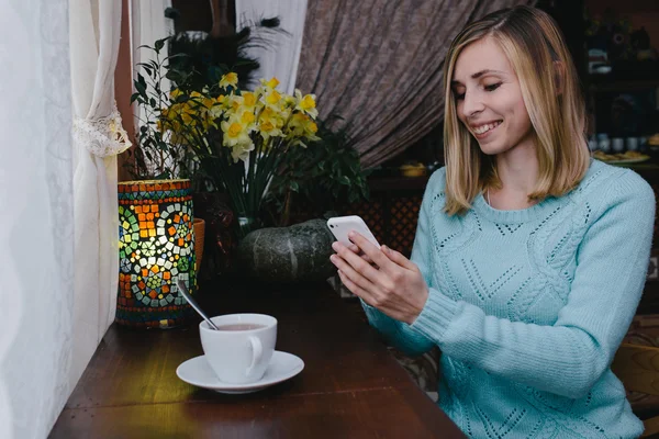 Charmante Frau mit schönem Lächeln, die gute Nachrichten auf dem Handy liest — Stockfoto