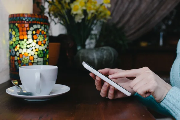 Frau tippt SMS auf Smartphone in Café am Holzweg — Stockfoto