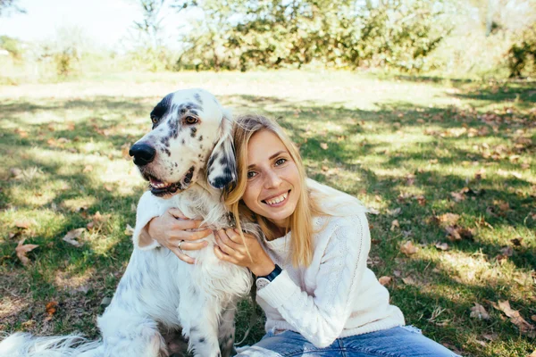 Feliz jovem mulher abraçando um grande cão branco no parque — Fotografia de Stock