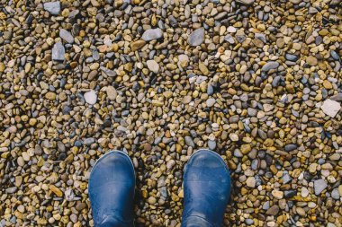 kadın bacakları koyu mavi kauçuk botlar ayakta ıslak çakıl