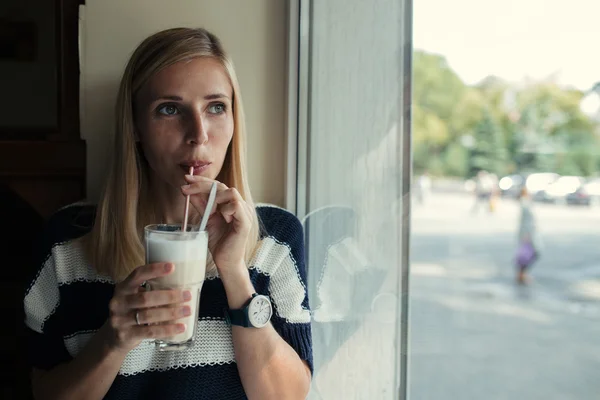 Porträt einer jungen Frau trinkt Kaffee Latte in Café am Fenster — Stockfoto