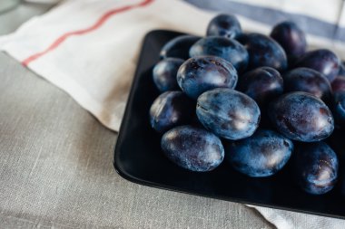 Kırsal bir masa örtüsü ve tekstil peçeteler ipe bir tabak ta Olgun erik