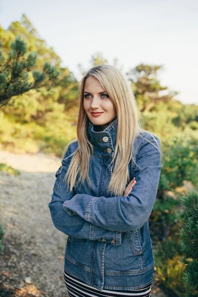 Portrait d'une belle jeune femme blonde veste en denim debout avec les mains pliées en plein air — Photo