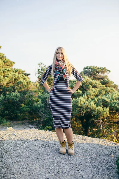 Belle jeune femme blonde dans une robe rayée, écharpe colorée et bottes jaunes en plein air — Photo