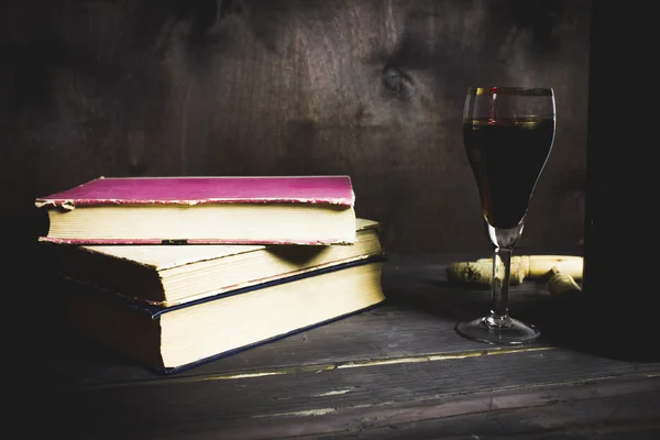 Copo de vinho tinto e velho livro aberto na mesa de madeira Fotografia De Stock