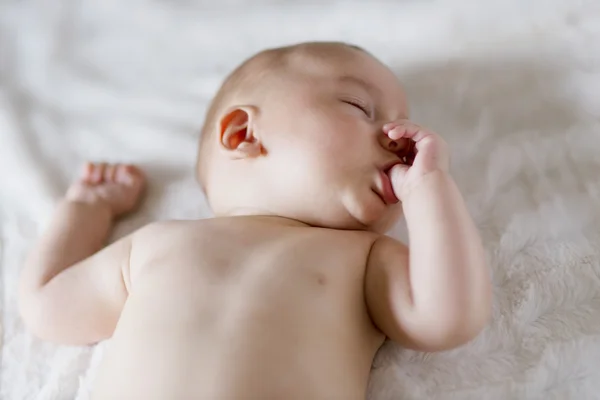 Recém-nascido nu bebê chupando dedo polegar na cama tempo deitado de volta no cobertor — Fotografia de Stock