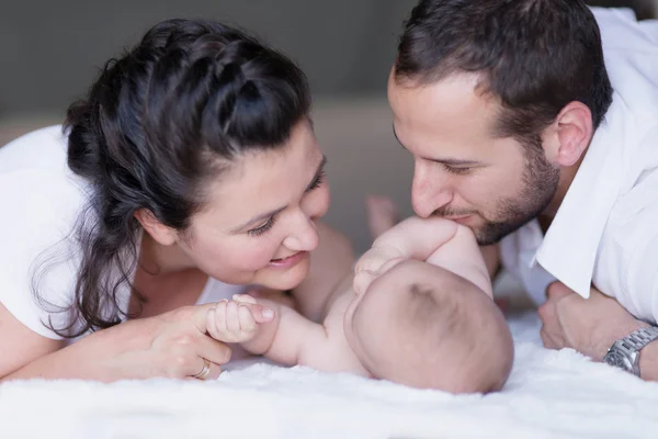 Родители взаимодействуют с новорожденным ребенком, целуют пальцы в холдинг — стоковое фото