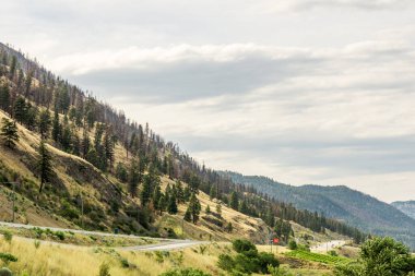 PEACHLAND, CANADA - 02 Ağustos 2020: Okanagan Vadisi 'ndeki küçük dağların tepesinde beyaz bulutlar.