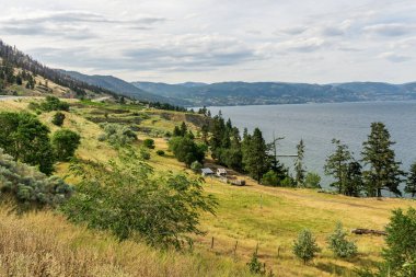 PEACHLAND, CANADA - 02 Ağustos 2020: Okanagan Vadisi 'ndeki küçük dağların tepesinde beyaz bulutlar.