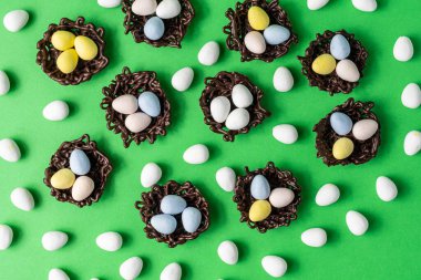 Küçük paskalya yumurtaları çikolata yuvalarında yeşil bir arka plan süslemesinde..