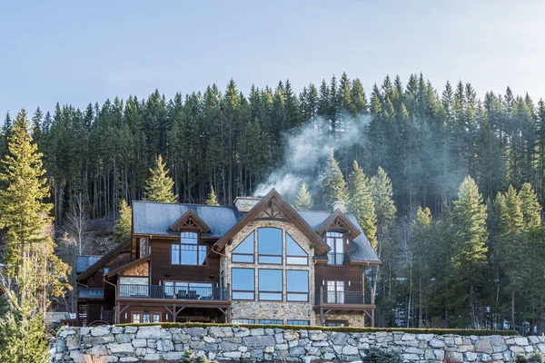 REVELSTOKE, CANADÁ - 16 DE MARZO DE 2021: Casa de madera de montaña en el bosque entre árboles altos — Foto de Stock