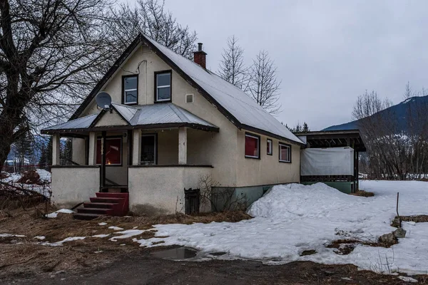 REVELSTOKE, CANADA - Março 14, 2021: casa velha em cidade pequena hora da noite início da primavera com neve — Fotografia de Stock