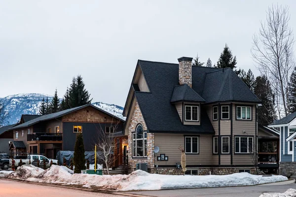 REVELSTOKE, CANADÁ - 14 DE MARZO DE 2021: casa privada y vista a la calle en la pequeña ciudad por la noche a principios de primavera con nieve — Foto de Stock