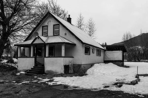 REVELSTOKE, CANADA - MARCH 14, 2021: black and white old house in small town evening time early spring with snow — Fotografia de Stock