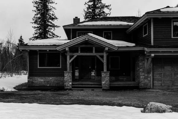 REVELSTOKE, CANADA - MARÇO 14, 2021: casa privada em preto e branco em cidade pequena hora da noite início da primavera com neve — Fotografia de Stock